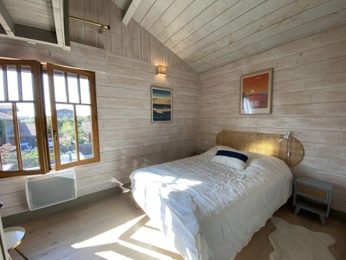 une chambre avec un lit dans une pièce aux murs en bois dans l'établissement L'ECLUSE maison tout confort piscine chauffée quartier prisé, à La Teste-de-Buch
