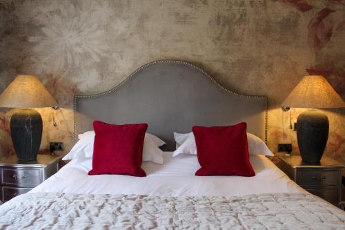 a bedroom with a bed with red pillows and two lamps at STAY on the High Street in Tarporley
