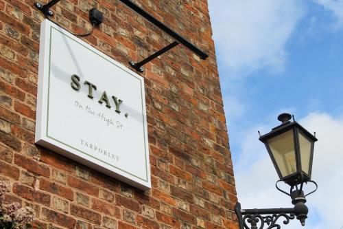 a sign on the side of a brick wall with a lamp at STAY on the High Street in Tarporley