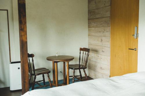1 Schlafzimmer mit einem Tisch, 2 Stühlen und einem Bett in der Unterkunft Masukichi 古民家宿ますきち 駐車場無料 in Seto