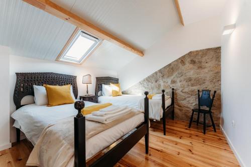 2 camas num quarto no sótão com uma parede de pedra em Quinta de S. Miguel 'Casa Das Oliveiras no Fundão