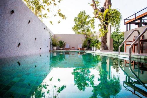 a swimming pool next to a building with trees at Cinnamon Hotel Bangkok in Bangkok