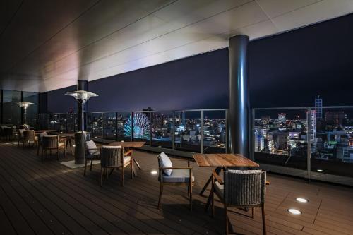 a rooftop bar with tables and chairs and a city skyline at SAPPORO STREAM HOTEL in Sapporo