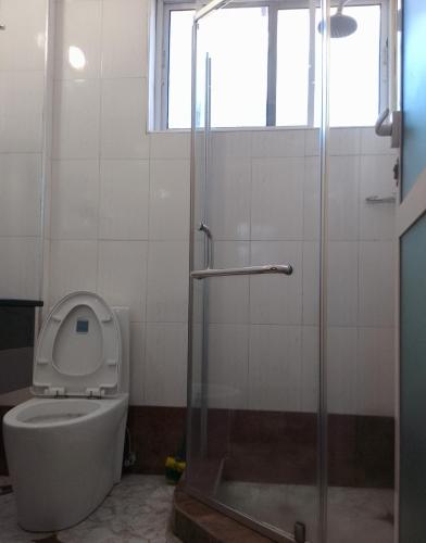 a bathroom with a toilet and a glass shower at Nemart's Hotel in Dar es Salaam