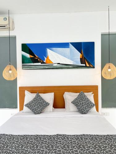 a bedroom with a bed with a painting of a boat at Apple Villas & Apartments in Kerobokan