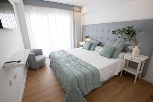 a bedroom with a large bed and a chair at FLEMING PLAYA PONIENTE in Benidorm
