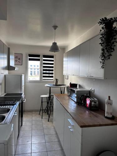 une cuisine avec des armoires blanches et un comptoir dans l'établissement Disney world Appart 10P , 5 min du parc, parking privé, à Chessy