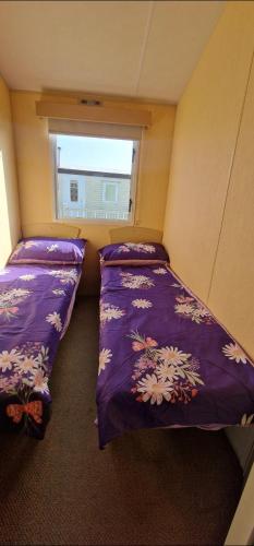 two beds in a small room with a window at Elle in Mablethorpe
