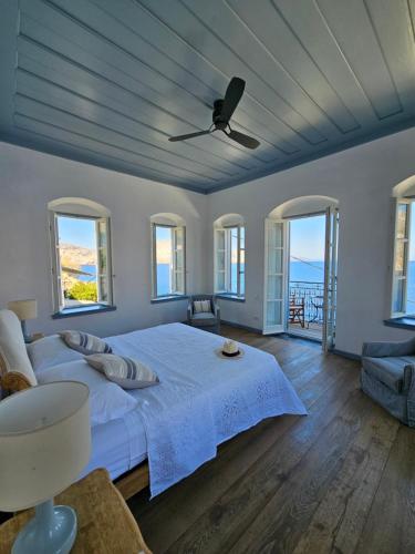 a bedroom with a large white bed with windows at The Anchor House in Symi