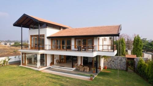 a large white house with a roof at SaffronStays Niranta- 4-BDR villa on golf course near Bangalore in Bengaluru