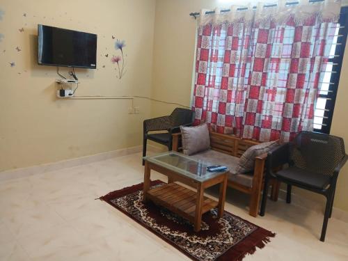 a living room with a couch and two chairs and a tv at LA SIESTA in Ooty