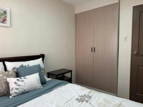 ein Schlafzimmer mit einem Bett mit einem Schrank und Kissen in der Unterkunft One Spatial Condominium, 2-Bedroom Unit #2920 in Iloilo City