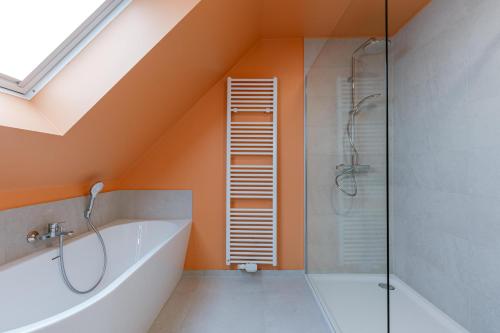 an attic bathroom with a shower and a bath tub at Flat Vigó in De Panne