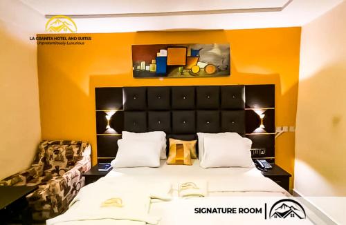 a bedroom with a large bed with an orange wall at LA GRANITA HOTEL AND SUITES in Ado Ekiti