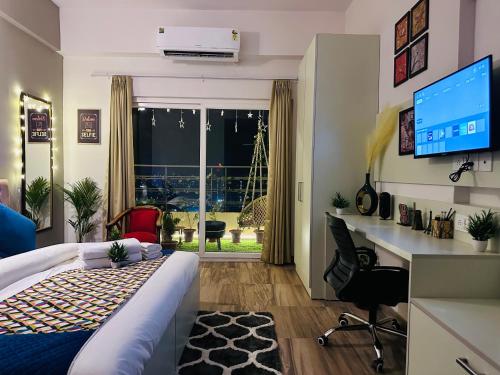 a bedroom with a bed and a desk and a television at Sapphire Skies By BuddiesHome in Greater Noida