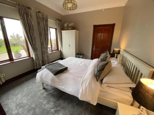 um quarto com uma cama com lençóis brancos e almofadas em Ravenwood em Castlebellingham