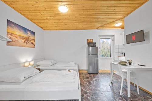 Habitación con 2 camas, mesa y nevera. en home2stay Apartmenthaus Deggendorf Wifi Smart TV Parking***, en Deggendorf