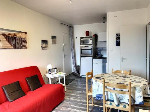 un salon avec un canapé rouge et une table dans l'établissement Appartement Familial Proche Plage et Forêt avec Parking Privé - FR-1-652-4, à Saint-Hilaire-de-Riez