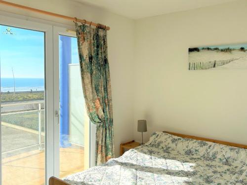 une chambre avec un lit et une porte coulissante en verre dans l'établissement Appartement bord de mer avec balcon, parking et commodités - FR-1-652-17, à Saint-Hilaire-de-Riez