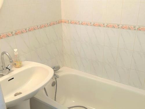 La salle de bains est pourvue d'un lavabo et d'une baignoire blanche. dans l'établissement Appartement bord de mer avec balcon, parking et commodités - FR-1-652-17, à Saint-Hilaire-de-Riez