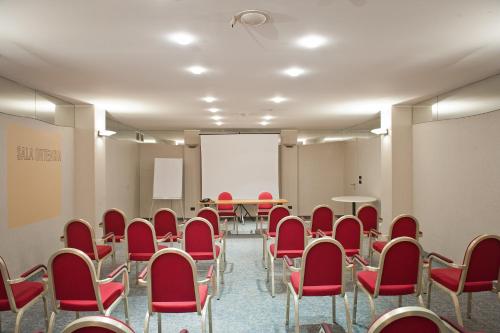 a conference room with red chairs and a white screen at Hotel Milano Alpen Resort Meeting&Spa in Castione della Presolana