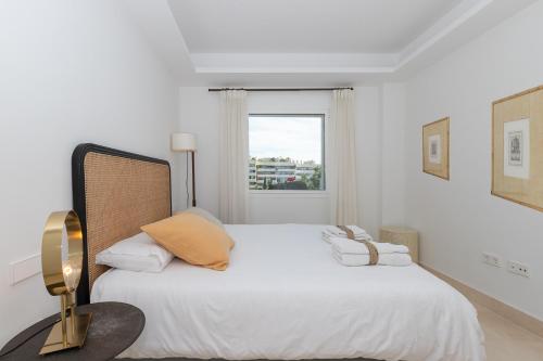 biała sypialnia z dużym łóżkiem i oknem w obiekcie Lujoso Apartamento con piscina en Paseo Maritimo Marbella w Marbelli