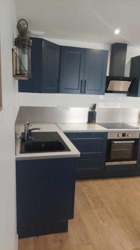 une cuisine avec des armoires bleues et un évier dans l'établissement Maison de ville - wifi - checkin autonome, à Saint-Martin-sur-Oust