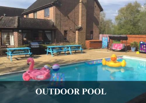 una piscina al aire libre con 2 juguetes inflables en el agua en The Fortis House, Bournemouth, with Swimming Pool and Hot Tub Jacuzzi en Bournemouth