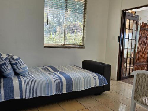 1 dormitorio con 1 cama con sábanas azules y blancas en Barieta Beach Cottages, en Umtwalumi
