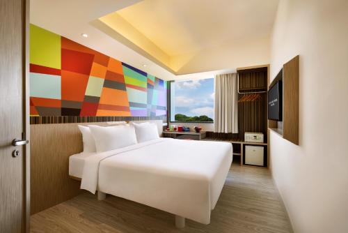 a bedroom with a white bed and a colorful wall at Genting Hotel Jurong in Singapore