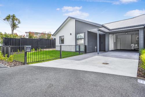 a house with a black fence and a driveway at Modern Retreat with King Bed - By KOSH BNB in Hamilton