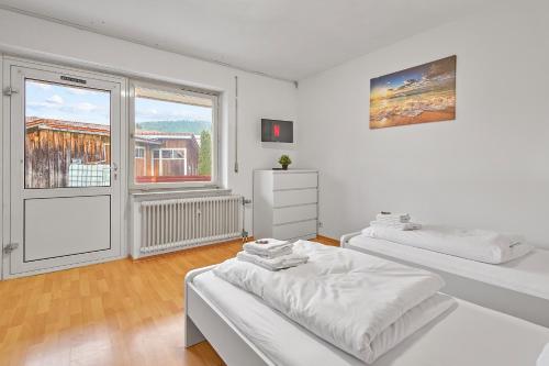 Habitación blanca con 2 camas y ventana en home2stay Apartmenthaus Deggendorf Wifi Smart TV Parking***, en Deggendorf