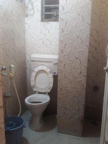 a bathroom with a toilet with a bucket in it at Hotel Raj Airport in kolkata