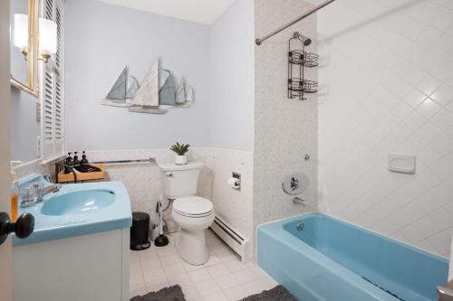 ein Badezimmer mit einer blauen Badewanne, einem WC und einem Waschbecken in der Unterkunft Federal on Exeter Circa 1805 Sleeps 8 in Exeter
