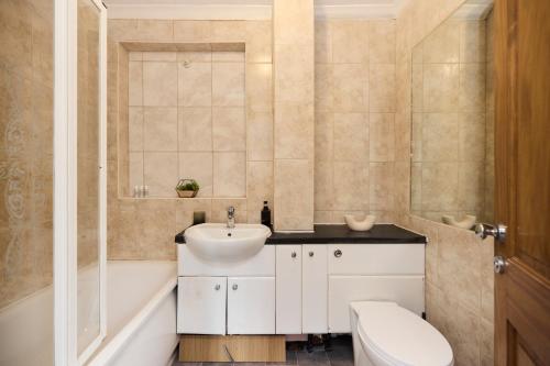 a bathroom with a sink and a tub and a toilet at The Enfield Place - Elegant 4BDR House with Garden in Winchmore Hill
