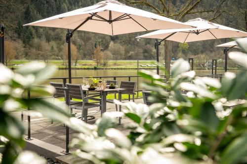 a table and chairs with umbrellas in front of a lake at Uferdeck - Boutique Hotel in Traben-Trarbach
