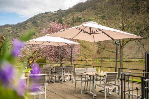 a patio with tables and umbrellas next to a river at Uferdeck - Boutique Hotel in Traben-Trarbach