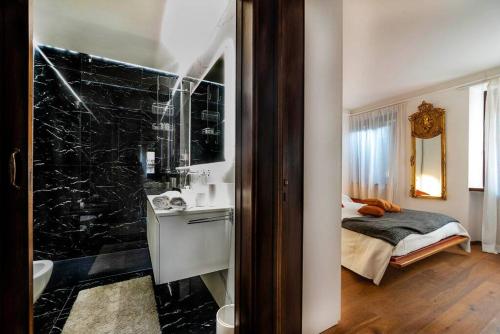 a bathroom with a black marble shower and a bed at Italianflat - Duomo Deluxe in Verona