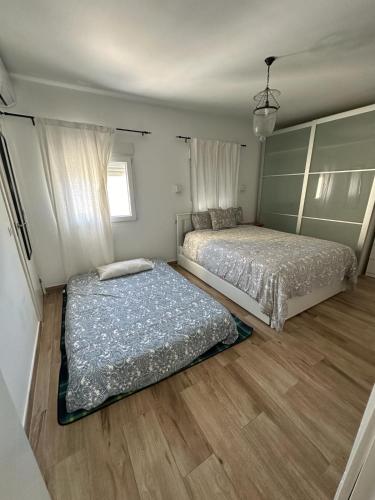 two beds in a bedroom with wooden floors at ATICO AMPLIO Y LUMINOSO in Seville