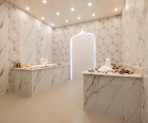 Khalidia Palace Hotel Dubai by Mourouj Gloria في دبي: غرفة بيضاء مع عدادات الرخام ومرآة