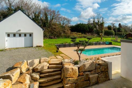 une maison avec un mur en pierre à côté d'une piscine dans l'établissement Villa Ti Vakansou - Avec piscine privée, à Clohars-Carnoët
