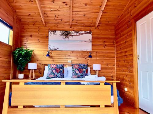 ein Schlafzimmer mit einem Bett in einer Holzwand in der Unterkunft House with bay views - St Helens family escape in St Helens