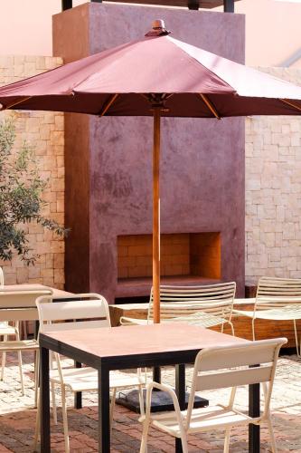 a table and chairs with an umbrella on a patio at Nosy Manga - Hotel Ivato Airport in Antananarivo