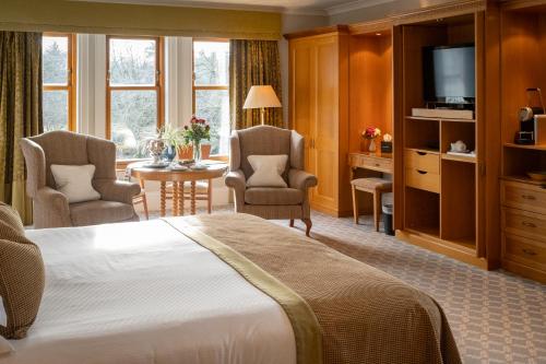 a hotel room with a bed and a desk and chairs at Lochgreen House Hotel & Spa in Loans