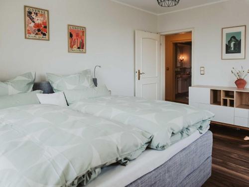 a white bedroom with a large white bed in it at Ferienwohnung Bodenseeblick in Allensbach