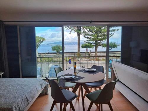 a room with a table and chairs and a view of the ocean at Estúdio Frente Mar in Horta