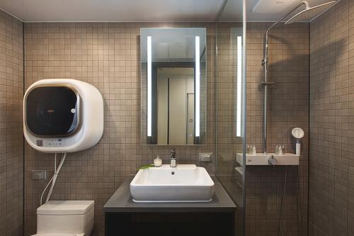 a bathroom with a sink and a toilet and a mirror at Haeundae Youngmu Parade Hotel in Busan