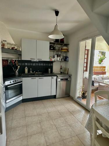 a kitchen with white appliances and a table with a table at Appartement Spacieux proche des Plages de la coudouliere in Six-Fours-les-Plages