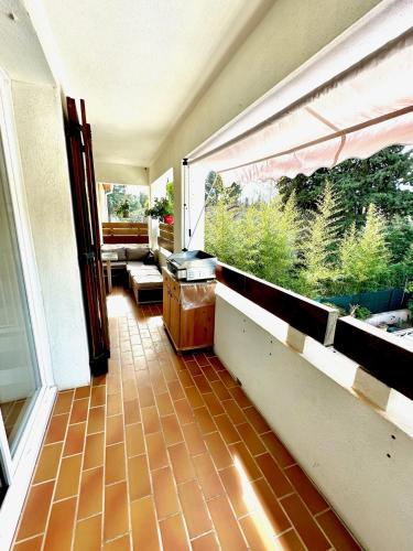 a room with a balcony with a view of a garden at Appartement Spacieux proche des Plages de la coudouliere in Six-Fours-les-Plages