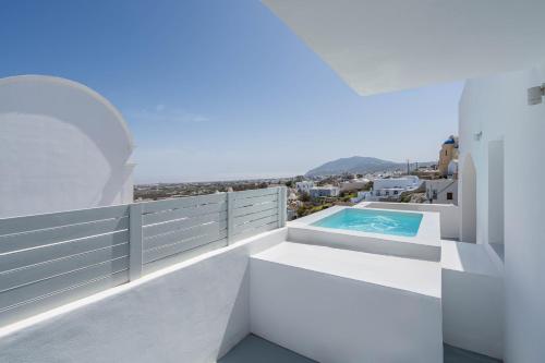 a white house with a swimming pool on the balcony at Cycladic Suites & Spa in Fira